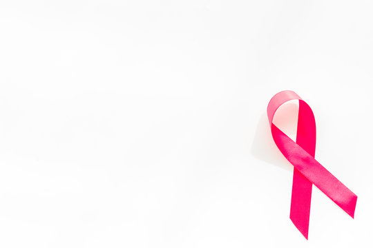Pink ribbon as symbol of breast cancer awareness on white background top view space for text