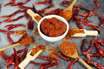curry paste cayenne pepper on wooden spoon spices and dried chilli peppers background / group of red hot chilli powder on black plate top view ingredients table asian food spicy