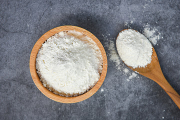 Fototapeta na wymiar Pastry flour on wooden bowl on gray background, top view - homemade flour on spoon for cooking ingredients on kitchen table