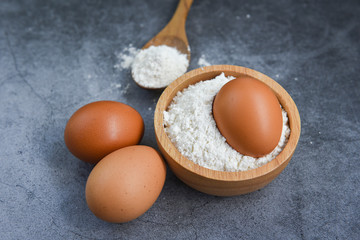 Pastry flour on wooden bowl on gray background, top view - homemade flour eggs cooking ingredients on kitchen table