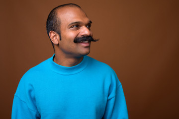 Face of happy Indian man with mustache wearing blue sweater