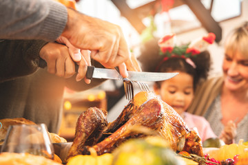 Thanksgiving Celebration Tradition Family Dinner Concept.family having holiday dinner and cutting turkey.Young black adult woman and her daughter happy..