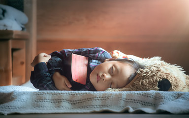 Cute little girl happily embracing a Bible and fell asleep. christian concept.