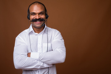 Portrait of happy Indian businessman with mustache as call center representative