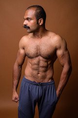 Profile view of muscular Indian man with mustache shirtless