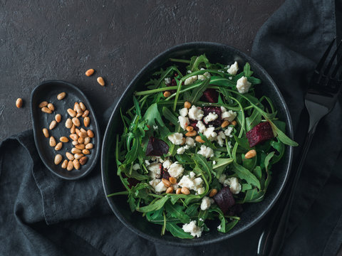 Beetroot, aragula and soft cheese salad over black background. Top view or flat lay. Copy space for text. Idea and recipe for healthy vegetarian salad. Clean eating diet concept