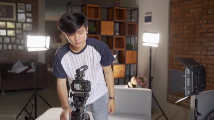 young man vlogger preparing lighting to create their vlog content at home