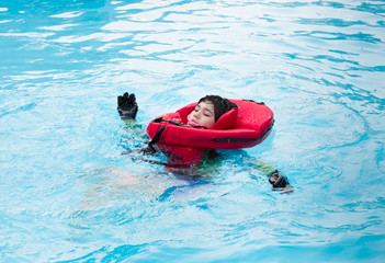 Special needs boy swimming in pool with life vest