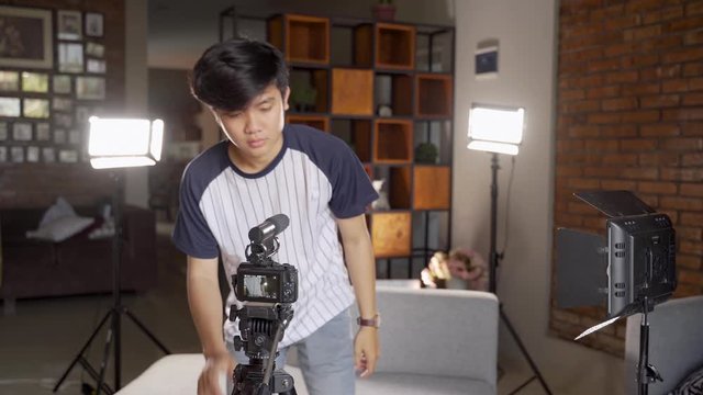 young man vlogger preparing lighting to create their vlog content at home