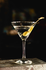Drink Dry Martini with Green Olives on Stone Background.