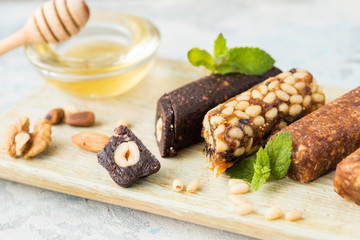 Bunch of mixed nuts bars with dried fruit & various nuts, wooden background. Healthy vegan super food, different fitness diet snacks for sporty lifestyle. Top view, copy space.