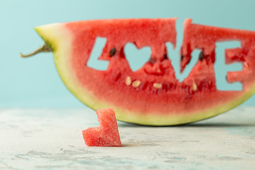 A slice of watermelon world Love, heart against the blue copy space. Watermelon with a hole in the shape of a heart. Summertime, watermelon lover, summer sale concept.