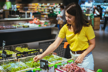 woman buying grapes in store