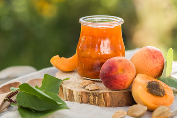 Apricot jam and ripe apricots on the wooden natural table.