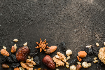 Mix of various nuts and raisins in scoop on old kitchen table. Top view.