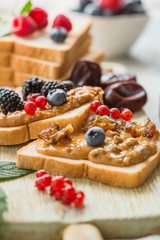 Toast bread with homemade strawberry jam and peanut butter. Homemade toast bread with jam and peanut butter on wood table for breakfast. Delicious toast bread ready to served. Toast bread with spread 