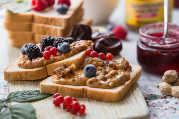 Toast bread with homemade strawberry jam and peanut butter. Homemade toast bread with jam and peanut butter on wood table for breakfast. Delicious toast bread ready to served. Toast bread with spread 