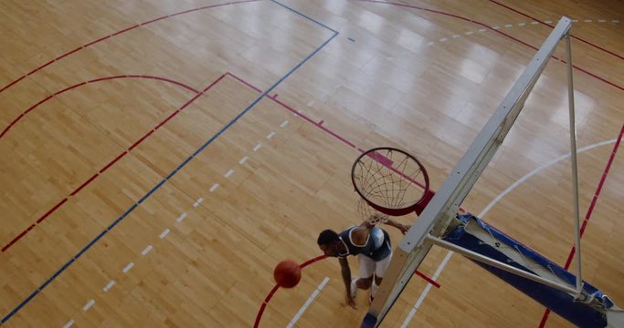 OVERHEAD HIGH ANGLE JIB SHOT African American black college male basketball player fails to dunk alone on the indoor court. 4K UHD 50 FPS SLOW MOTION RAW Graded footage