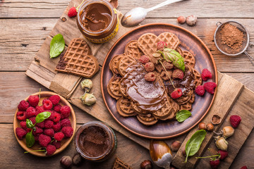 Belgium waffles heart with chocolate sauce raspberries on wood background.