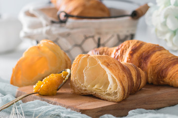 Freshly baked croissants with orange jam on light background