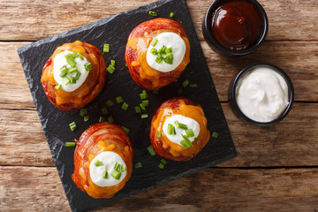 Tasty hot appetizer volcano baked potatoes with bacon, cheese and onions close-up. Horizontal top view