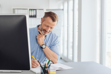 Thoughtful businessman writing notes in the office