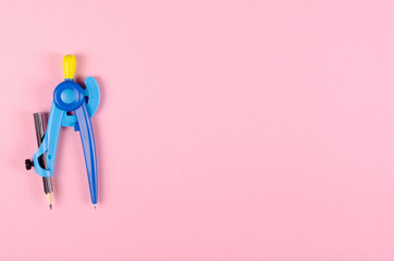 Blue stationery compass for kids on pink background.