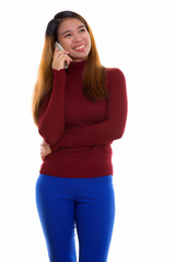 Studio shot of young Asian woman with turtleneck sweater using phone