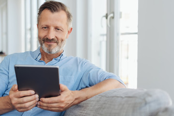 Attractive man relaxing on a sofa with a tablet-pc