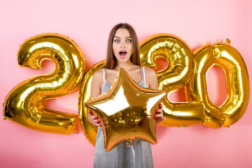 happy woman with golden new year 2020 balloons isolated over pink
