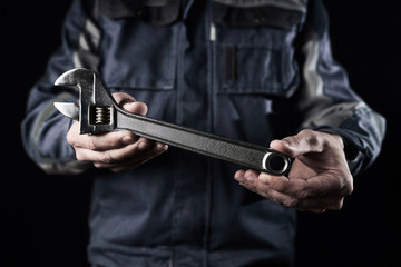 Professional construction worker shows a wrench on a dark background