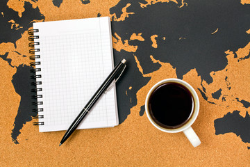 Cup of black hot coffee on a map with pen and notepad. Top view.