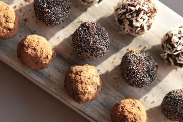 Homemade healthy energy vegan raw sweet balls made of dried fruits and nuts on wooden plate. Dessert with no added sugar, healthy diet food concept. Selective focus. Top view, flat lay.         