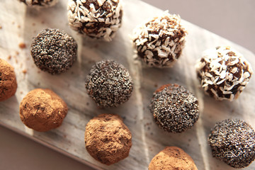 Homemade healthy energy vegan raw sweet balls made of dried fruits and nuts on wooden plate. Dessert with no added sugar, healthy diet food concept. Selective focus. Top view, flat lay.         