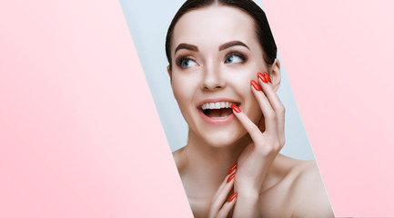 Portrait of model with natural nude make up with bare shoulders. Beautiful young woman with perfect glow clean skin look into the hole of pink, blue paper.