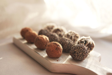 Homemade healthy vegan raw sweet balls made of dried fruits and nuts on wooden plate. Diet dessert with no added sugar, healthy diet gluten free food concept. Selective focus.         