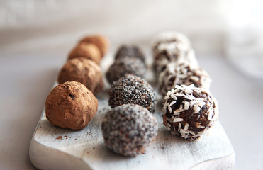Homemade healthy vegan raw sweet balls made of dried fruits and nuts on wooden plate. Diet dessert with no added sugar, healthy diet gluten free food concept. Selective focus.         