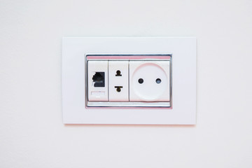 a socket on a light gray wall, a multifunction outlet with an internet connection . Electric light switch and socket on the empty wall, electrical power socket and plug switched .