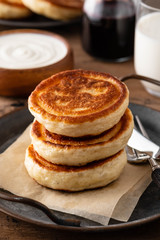 Homemade pancakes stack with milk and jam on wooden background.