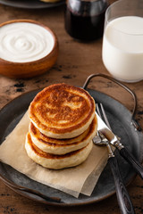Homemade pancakes stack with milk and jam on wooden background.