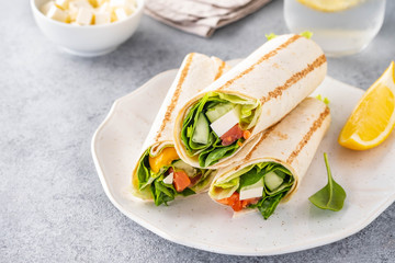 Wrap sandwich, roll with fish salmon, vegetables and cheese. Grey background. Close up.