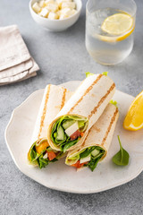 Wrap sandwich, roll with fish salmon, vegetables and cheese. Grey background. Close up.