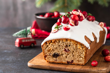 Christmas cake with cranberries and Christmas decorations on a dark background.
