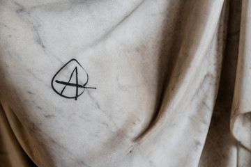  A symbol of anarchy drawn on marble sculpture. Vandalism symbol.