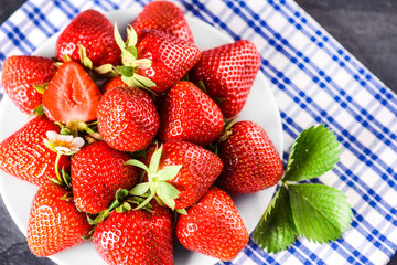 Many fresh strawberries from top view. Sweet perfect strawberry fruits on table with green leaves.