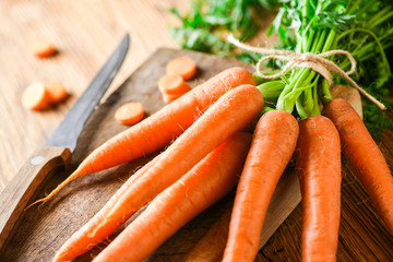 Fresh carrot vegetable from healthy garden on wooden table. Cut carrots bunch with knife top view.