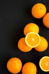 Ripe organic oranges on a black surface, top view. Flat lay, overhead, from above. Copy space.