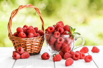 Fresh beautiful raspberry in glass cup on white table.
