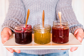 Housewife at home show hand made fresh marmalades to the camera - close up of healthy fresh fruit food for breakfast - colors and background with unrecognizable people