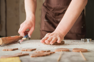 Fototapeta na wymiar Men's hands and dough close-up. Baking gingerbread Christmas and Easter gingerbread cookies. A man in the kitchen is preparing cookies in an apron and copy space.